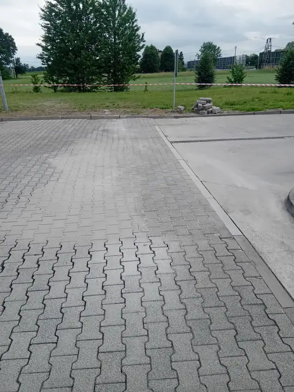 Opaska z kostki brukowej poprowadzona wzdłuż ściany budynku, z wykończoną krawędzią