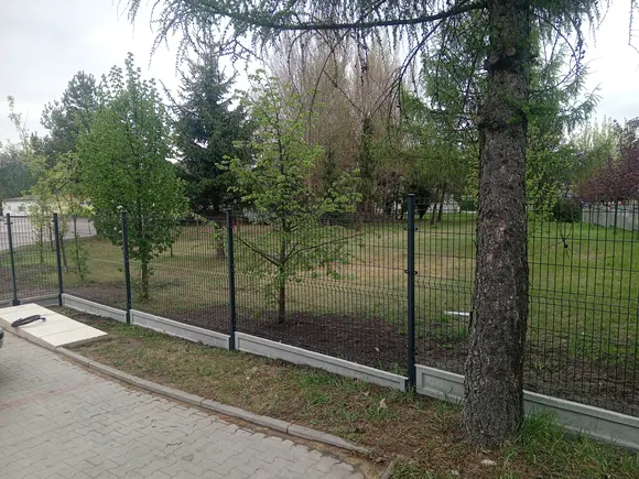 Ogrodzenie z siatki rozpiętej na słupkach, z furtką prowadzącą na działkę